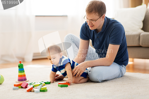 Image of happy father with baby son playing toys at home