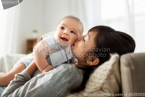 Image of happy mother kissing little baby son at home