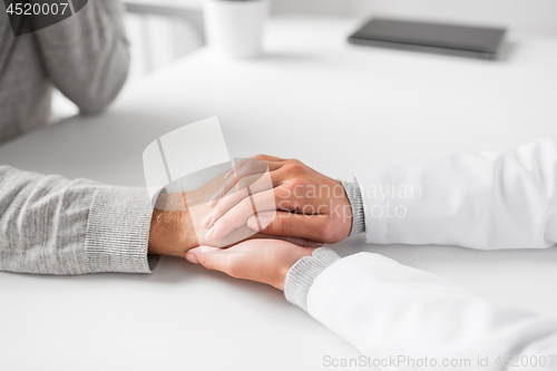 Image of close up of doctor holding senior patient hand