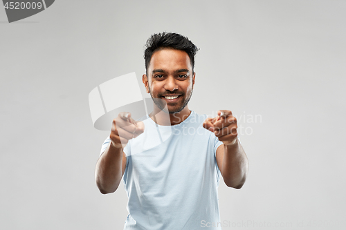 Image of smiling indian man pointing fingers at you