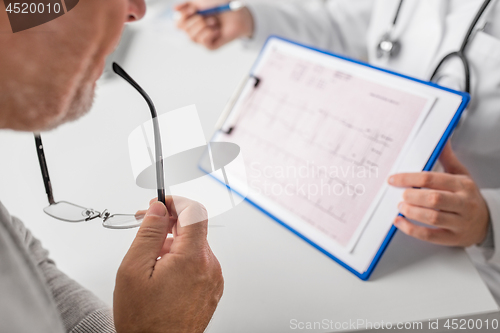 Image of senior man and doctor with cardiogram at hospital