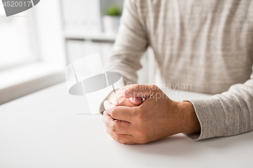 Image of senior man hands on table