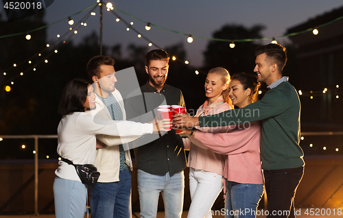 Image of friends clinking party cups on rooftop at night