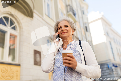 Image of senior woman calling on smartphone in city