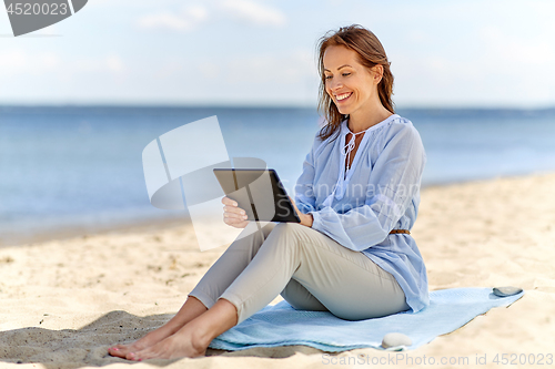 Image of happy smiling woman with tablet pc on summer beach