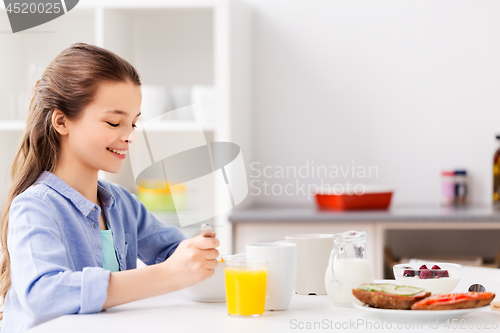 Image of happy girl having breakfast at home