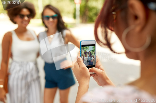 Image of woman photographing her friends in summer park