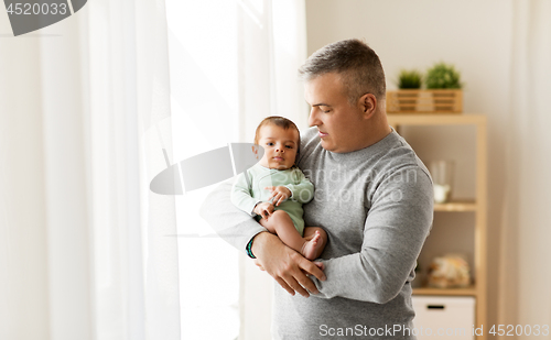 Image of happy father holding with little baby son at home