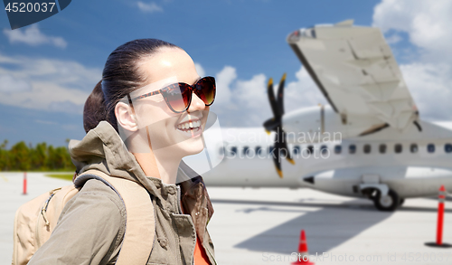 Image of young woman with backpack over plane on airfield