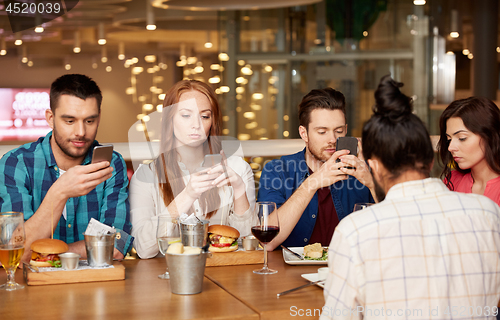 Image of friends with smartphones at restaurant