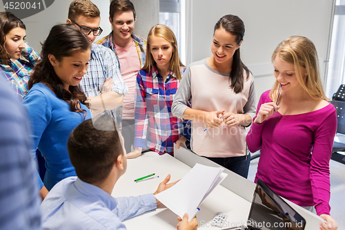 Image of students and teacher with papers and laptop