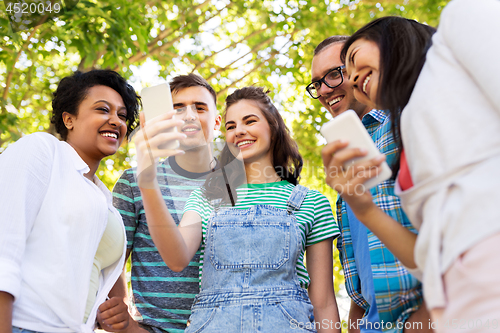 Image of happy friends with smartphone at summer park