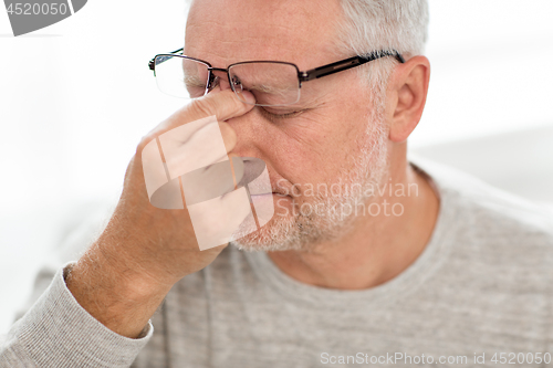 Image of senior man in glasses massaging nose bridge