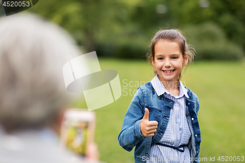 Image of girl being photographed and showing thumbs up
