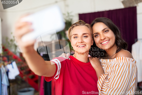 Image of female friends taking selfie at clothing store