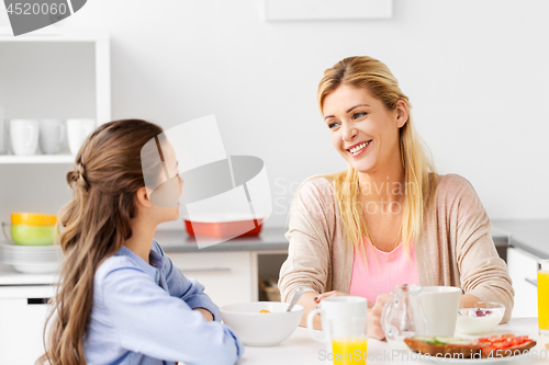 Image of happy mother and daughter having breakfast at home