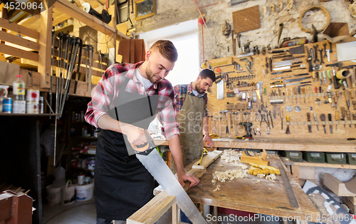 Image of carpenters working with saw and wood at workshop