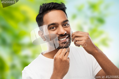 Image of indian man with dental floss cleaning teeth