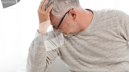 Image of senior man suffering from headache at home