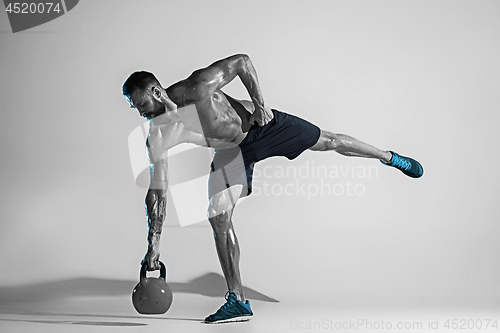 Image of Young caucasian bodybuilder training over studio background