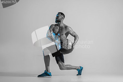 Image of Young caucasian bodybuilder training over studio background