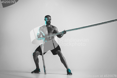 Image of Young caucasian bodybuilder training over studio background