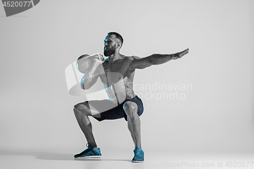 Image of Young caucasian bodybuilder training over studio background