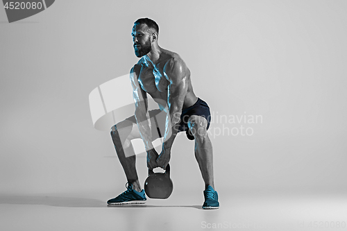 Image of Young caucasian bodybuilder training over studio background