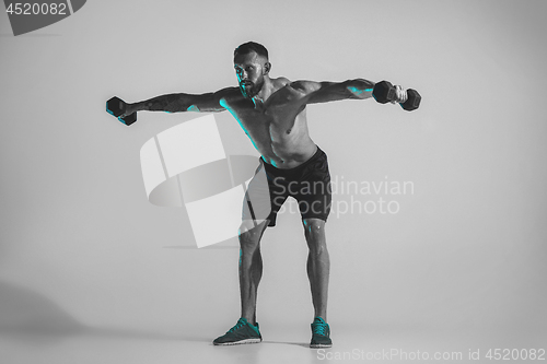 Image of Young caucasian bodybuilder training over studio background