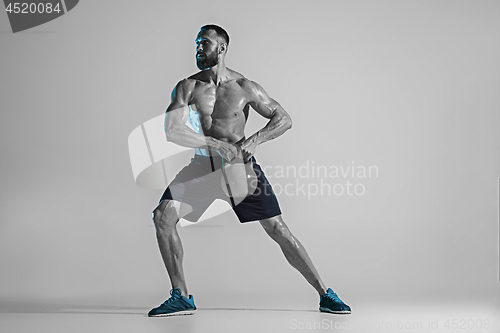 Image of Young caucasian bodybuilder training over studio background