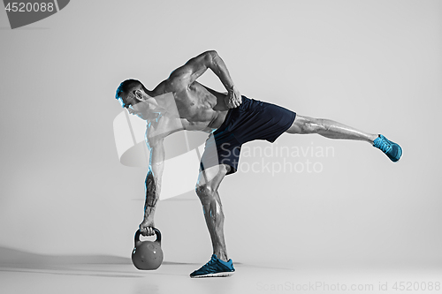 Image of Young caucasian bodybuilder training over studio background