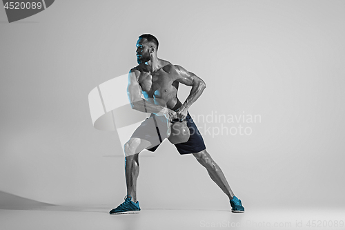 Image of Young caucasian bodybuilder training over studio background