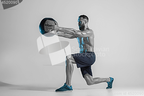 Image of Young caucasian bodybuilder training over studio background