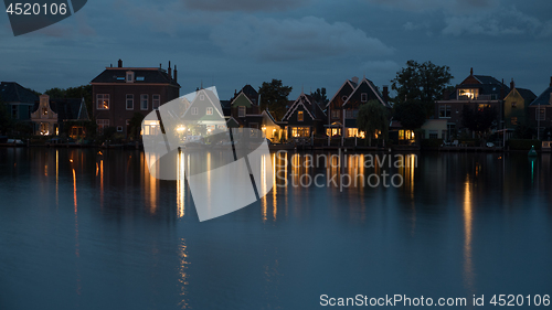 Image of Waterside Dutch village with lights reflection on water at night