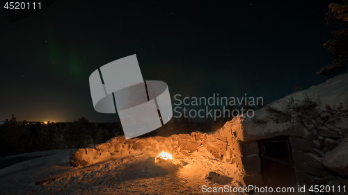 Image of Warm light of the fire and polar lights in night sky