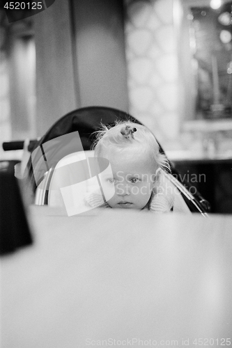 Image of Baby girl in stroller watching cartoons on cellphone