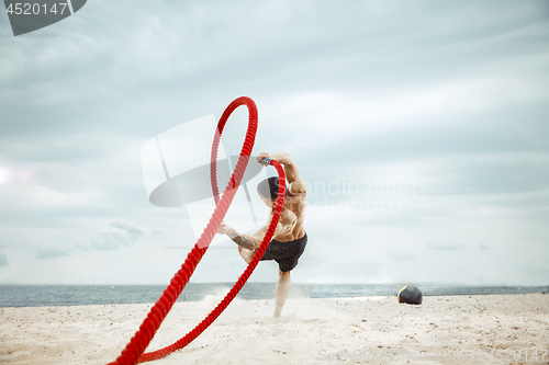 Image of Young healthy man athlete doing squats at the beach