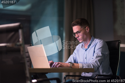 Image of man working on laptop in dark office