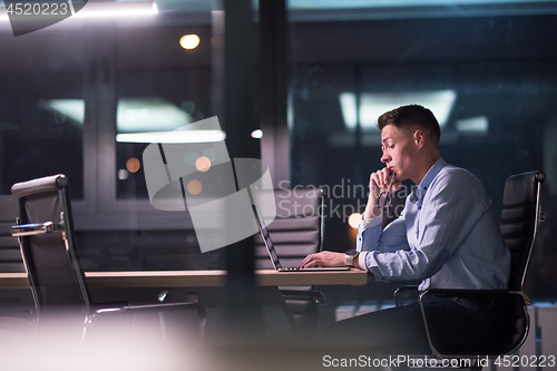 Image of man working on laptop in dark office