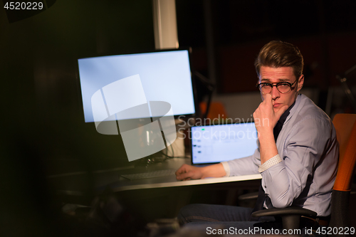 Image of man working on computer in dark office