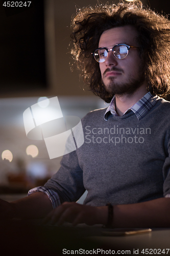 Image of man working on computer in dark office