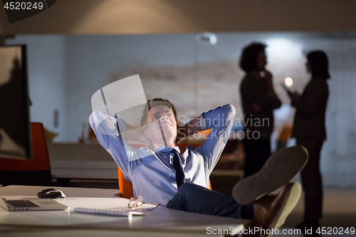 Image of businessman sitting with legs on desk at office