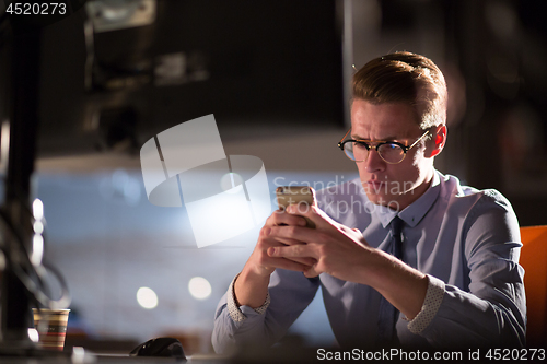 Image of man using mobile phone in dark office