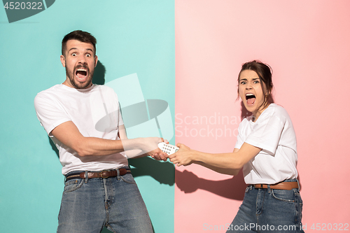 Image of young couple watching tv and fighting to get the remote control