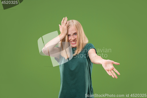 Image of Beautiful female half-length portrait isolated on green studio backgroud. The young emotional surprised woman