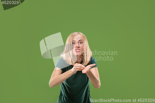 Image of Beautiful female half-length portrait isolated on green studio backgroud. The young emotional surprised woman