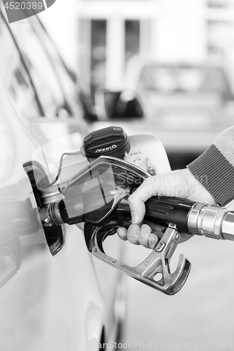 Image of Closeup of mans hand pumping gasoline fuel in car at gas station.