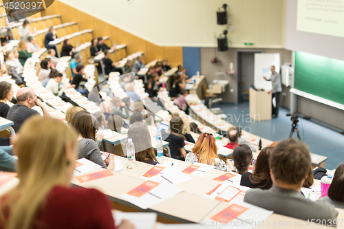 Image of Audience in the lecture hall. Female student making notes.