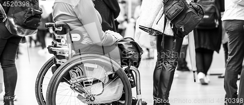 Image of Close up of unrecognizable hanicapped woman on a wheelchair queuing in line to perform everyday tasks.