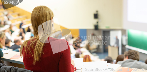 Image of Female student attending faculty lecture workshop making notes.